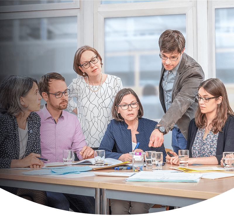 Banner Medizinstudium, Professor Kadmon und ihr Team um einen Tisch mit Dokumenten  (Foto)