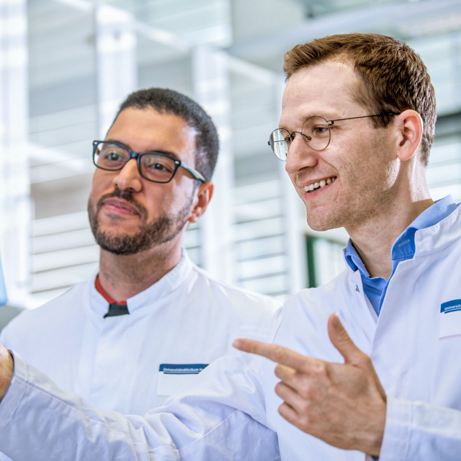 Zwei Wissenschaftler betrachten gemeinsam eine durchsichtige Folie mit Linien.