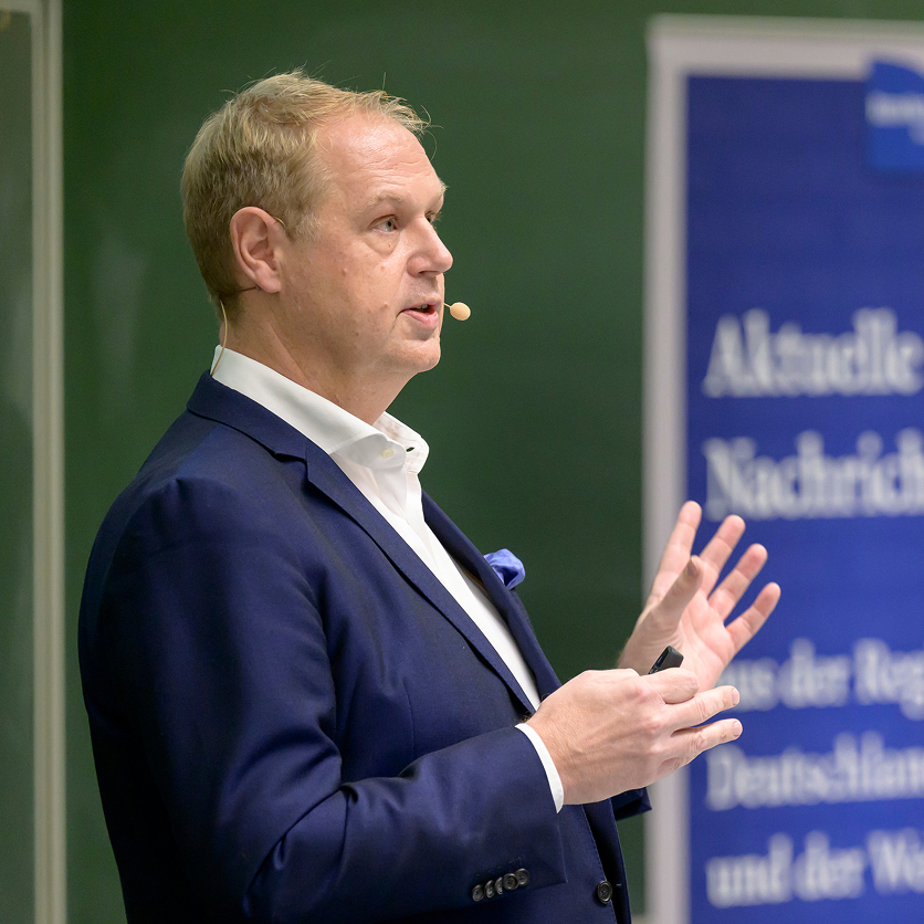 Prof. Dr. Norbert Frey mit Mikrofon bei einem Vortrag im Rahmen der Reihe ‚Medizin am Abend‘.