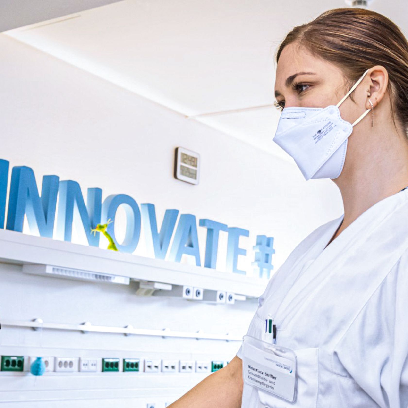 Eine junge medizinische Fachkraft mit Mundschutz, im Hintergrund ist der Schriftzug „Innovate#“ zu sehen.