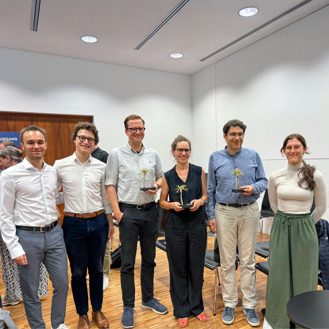 Gruppenfoto zur Verleihung des PaLMe-Lehrpreises: Die Personen stehen lächelnd nebeneinander, die drei Preisträger*innen halten eine silberne Palme in den Händen.