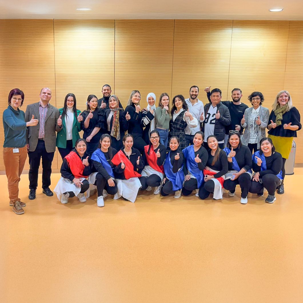 Gruppenfoto neuer internationaler Pflegekräfte am Universitätsklinikum Heidelberg. Die Personen stehen lächelnd nebeneinander.
