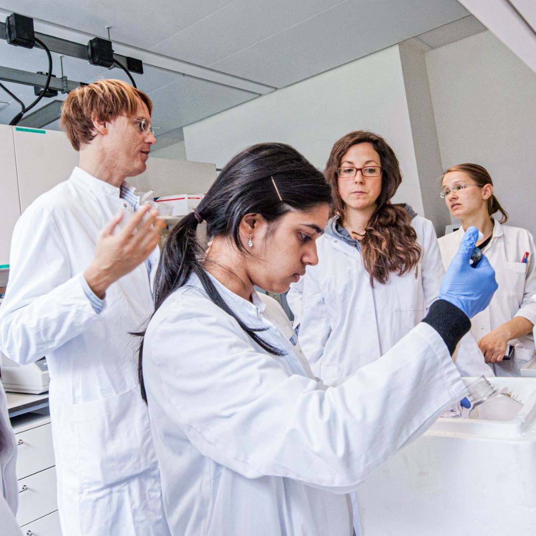 Medizinstudierende in weißen Kitteln üben praktische Fertigkeiten im Labor.